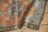 Distressed Oushak rug shows madder red, slate blue geometric border, and even pile wear.