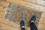 Central diamond medallion and distressed texture on the vintage Oushak rug in aubergine and slate.
