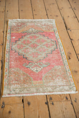 Faded pink, beige, and teal distressed Oushak rug with floral medallion and stepped outlines.