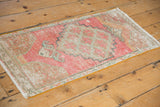 Distressed Oushak rug's faded pink, ivory texture with green outlines and intact side cord.