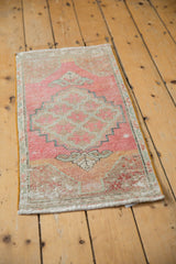Distressed Oushak rug corner: pink, beige, teal, showing stepped pattern and worn pile.