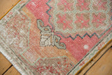 Distressed pink and beige Oushak rug corner showing worn pile and lattice floral details.