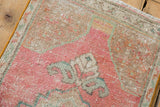 Close-up of distressed Oushak rug pile with pink, beige, and sea foam green tones.