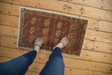 Distressed Oushak rug corner with even wear, featuring chestnut and teal floral motifs.
