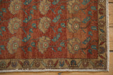 Distressed Oushak rug corner showing worn chestnut, teal, ivory floral motifs, border, and fringe.