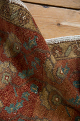 Folded detail of vintage distressed Oushak rug, showing chestnut, ivory, and aqua floral motifs.
