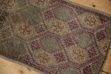 Distressed Oushak rug close-up showing worn geometric floral pattern in brown and aubergine.