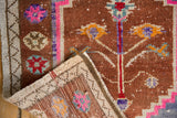Folded corner of the distressed Oushak rug, showing textured pile, vibrant motifs, and woven back.