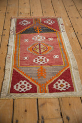 Distressed Jijim rug featuring geometric guls in wine red, tangerine orange, and ivory.