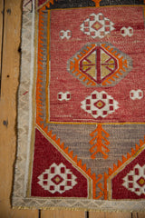 Hand woven Vintage Distressed Jijim rug corner with red geometric gul, orange plant, and fringe.