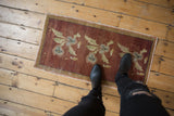 Copper distressed Oushak mat with faded floral bouquet motifs and worn pile.