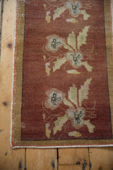 Corner of distressed Oushak runner showing worn copper pile and thin beige border.