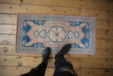 Distressed Oushak rug with pale sapphire blue medallion, dusty rose field, and even wear.