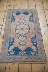 Pale sapphire blue and dusty rose border with pinwheel floral details on a distressed Oushak rug.