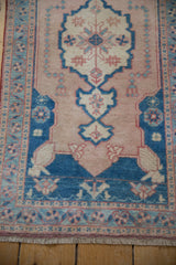 Distressed Oushak rug detail: lower pale sapphire blue medallion point and dusty rose pearl-adorned field.