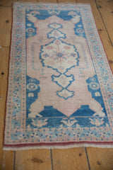Distressed vintage Oushak rug runner showing pale sapphire blue floral border and red selvage.