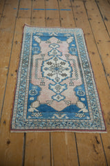 Distressed pale blue and dusty rose central medallion with meandering vine border detail.