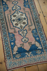 Distressed Oushak runner's soft dusty rose field with pearl motifs and blue floral border.