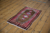 Distressed Oushak rug corner, showing pink rams horn motifs and geometric diamond border.