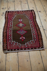 Distressed Oushak rug corner with burgundy rams horn border, orange diamond motifs, fringe.