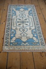 Distressed Oushak rug border with meandering floral vines in pale blue and ivory.