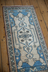 Distressed Oushak rug corner with meandering floral border in pale blue and ivory.