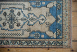 Corner of distressed vintage Oushak rug with powder blue, ivory floral borders and worn selvage.
