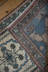 Folded vintage Oushak rug displaying its distressed texture, ivory field, and blue floral border.