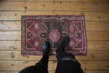 Distressed Oushak rug showcasing simplistic floral gul, purple, fuchsia, and oxidized tones.
