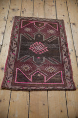 Corner of a distressed Oushak rug mat, revealing fuchsia geometric patterns and oxidized silver tones.