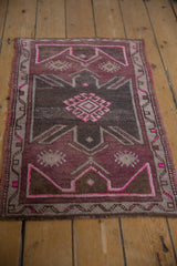 Distressed Oushak rug corner showing purple, fuchsia, and ivory geometric patterns with even wear.