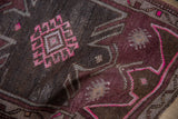 Distressed pile of Oushak rug, showing vivid fuchsia geometric motifs and softened brown tones.