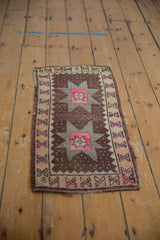 Distressed chocolate brown, ivory, and pink floral cross-section border on vintage Oushak rug.