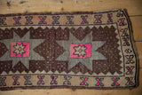 Vintage distressed Oushak rug corner with chocolate brown, silver, and bright pink geometric motifs.