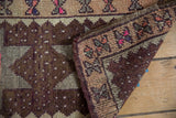 Folded vintage Oushak rug showing distressed chocolate brown, ivory, pink floral border.
