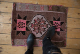 Distressed vintage Oushak rug showing central pink floral medallion and geometric brown starbursts.