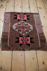 Distressed Oushak rug, pink starburst geometric motif on a brown field with fringe.
