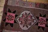 Distressed Oushak rug close-up showing pink curvilinear floral and starburst geometric motifs.