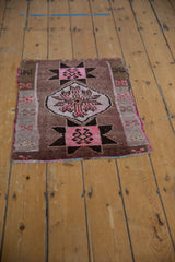 Pink and dark brown starburst geometric motif on a distressed Oushak rug corner.