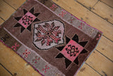 Distressed vintage Oushak rug detail: pink starburst motif, brown field, and soft gray border.