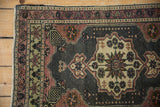 Distressed Oushak rug corner showcasing dusty mauve meandering vine border and oxidized silver field with even wear.