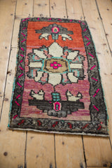 Vibrant fuschia floral medallion detail on a distressed Oushak rug's abrashed ground.
