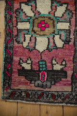 Distressed vintage Oushak rug showing short pile, vibrant fuchsia, beige patterns, and turquoise selvage.
