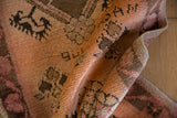 Folded vintage distressed Oushak rug, highlighting soft terracotta and faded blush short pile.