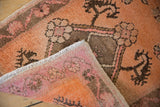 Distressed Oushak rug corner: short, even pile texture with terracotta and faded raspberry.