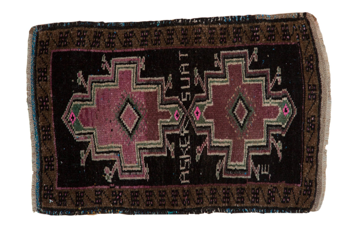 Vintage distressed Oushak mat with two geometric medallions in mauve on a charcoal black field.