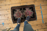 Small distressed Oushak rug mat with geometric mauve medallion, shown for scale.