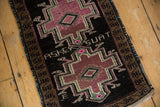 Inscribed weaver's name on the charcoal black field of a distressed vintage Oushak rug.
