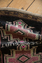 Weaver's inscription and textured mauve pile on a folded vintage distressed Oushak rug mat.