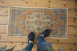 Vintage distressed Oushak rug mat with faded rust, pale blue, and ivory tones underfoot.